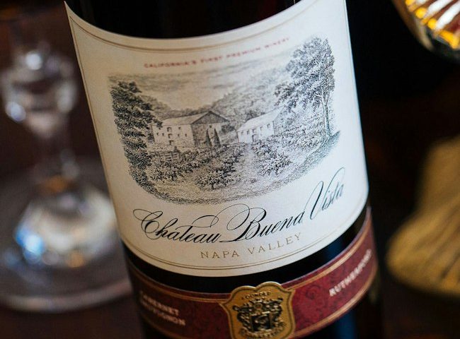 Label pada sebotol wine tampak dari dekat, menampilkan nama produsen, kawasan asal, dan tahun panen anggur.