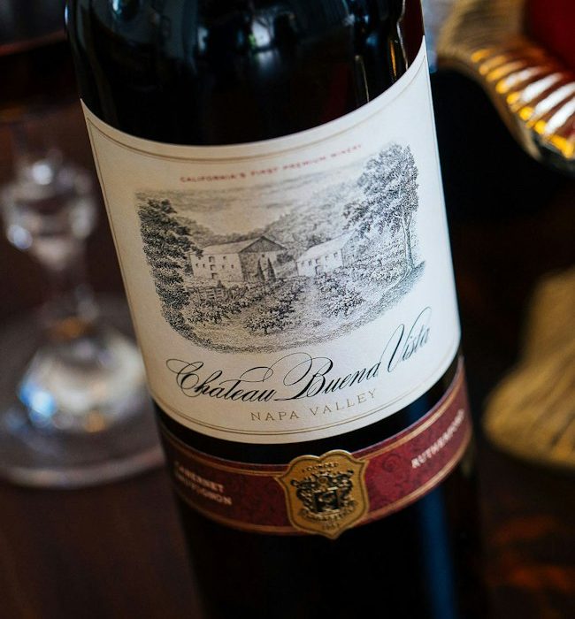 Label pada sebotol wine tampak dari dekat, menampilkan nama produsen, kawasan asal, dan tahun panen anggur.
