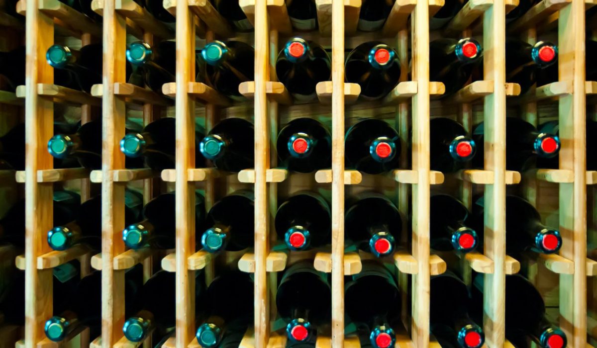 Cara Menyimpan Wine di Rumah dengan Benar agar Rasanya Tetap Prima 1 Botol-botol wine tersusun rapi dalam posisi miring di rak gudang penyimpanan yang sejuk dan remang.
