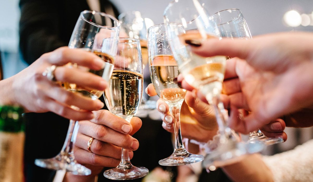 Dua gelas sparkling wine diangkat untuk bersulang merayakan momen spesial bersama.