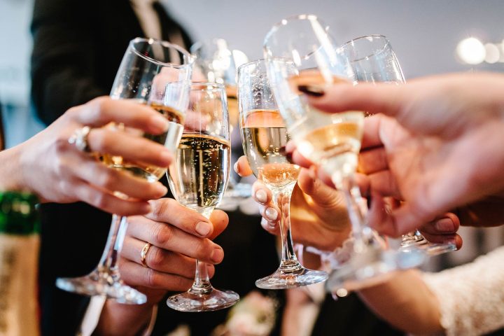 Dua gelas sparkling wine diangkat untuk bersulang merayakan momen spesial bersama.