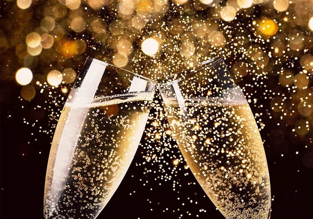 Memilih Wine untuk Perayaan: Sparkling, White, dan Red Sesuai Momen 2 Gelas-gelas sparkling wine diangkat dan dibenturkan untuk bersulang dalam sebuah perayaan.