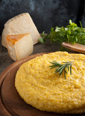 A plate of golden mămăligă, the traditional Moldovan cornmeal dish served with cheese, sour cream and hearty sides.