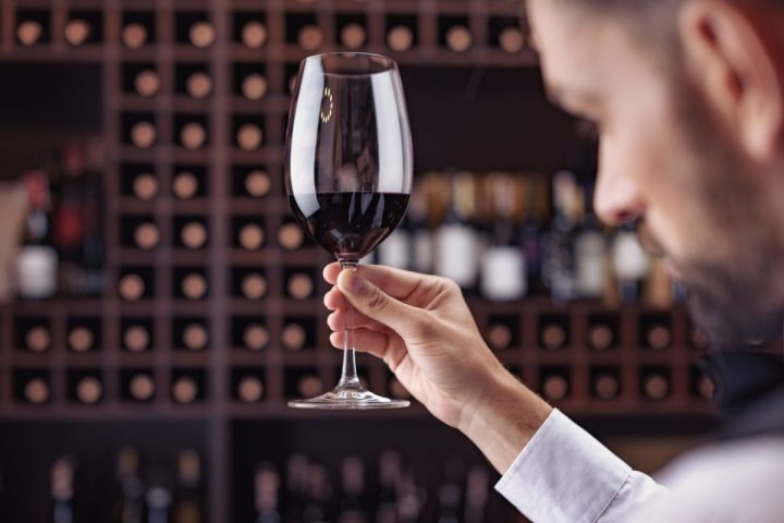 Istilah Penting Dunia Wine: Glosarium Lengkap untuk Pemula 9 Seorang sommelier sedang mencicipi wine dari gelas untuk menilai aroma dan rasanya.